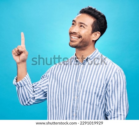 Point, thinking and man on blue background for news, information and announcement in studio. Advertising, mockup sign and face of excited male pointing for copy space, promotion and showing gesture