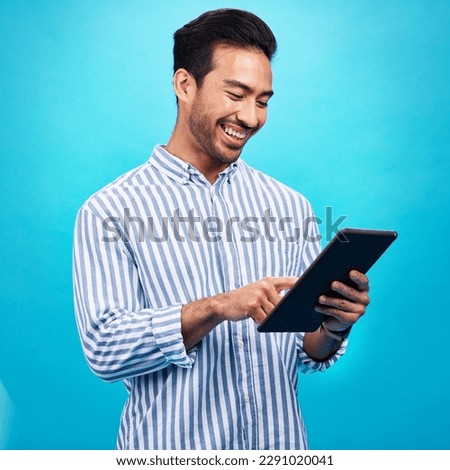 Tablet, man and smile in a studio on social media, internet and website app scroll. Happiness, isolated, and blue background with a male model reading a ebook on a digital networking application