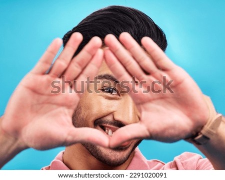 Frame, hands and portrait of Asian man on blue background with smile, confidence and happiness. Perspective, framing and face of happy male in studio for photography, profile picture and vision sign