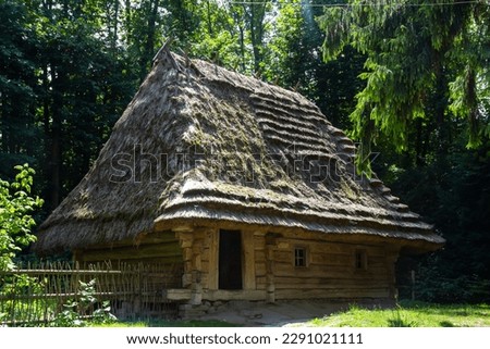 Traditional Ukrainian old house under a thatched roof on the background of the forest on a summer sunny day. Royalty-Free Stock Photo #2291021111