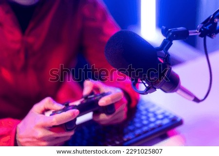 Professional gamer casting podcast walkthrough review. Young asian man sitting on chair with computer pc and microphone. Happy male Streamer wearing headphone playing game online in room neon light Royalty-Free Stock Photo #2291025807