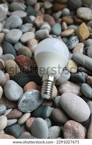 Vertical Photo Of LED Bulb With E14 Basement Lying On Smooth Sea Stones  Royalty-Free Stock Photo #2291027671