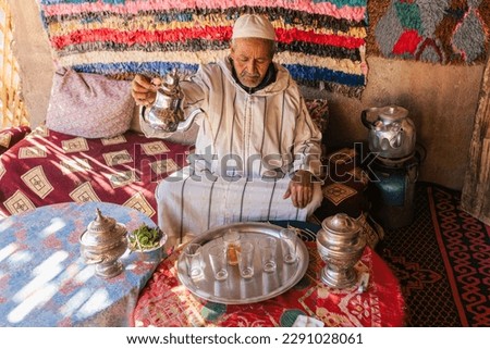 Moroccan man in traditional dress doing ritual preparation of mint tea on outdoor terrace Royalty-Free Stock Photo #2291028061