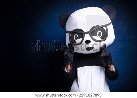 Man in panda costume on dark background.