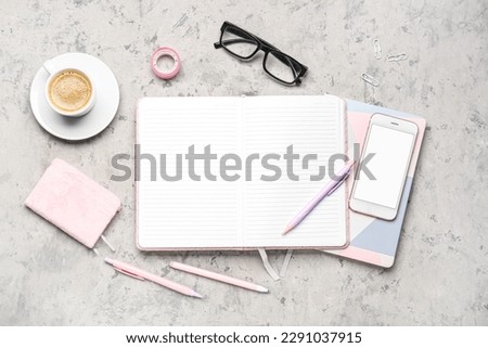 Composition with notebook, mobile phone, pens, glasses and cup of coffee on grey table