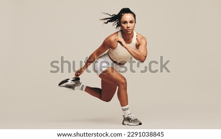 Young female athlete performing strength training exercises in a studio. Sportswoman showing her dedication to improving her body fitness and performance through intense workout techniques. Royalty-Free Stock Photo #2291038845
