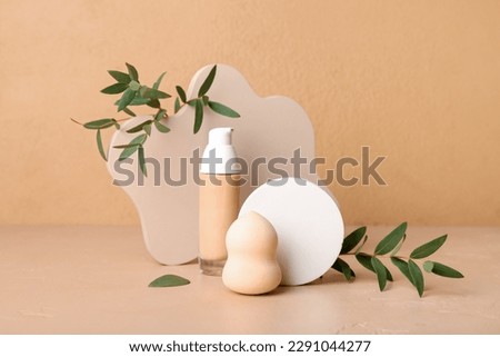 Decorative plaster podiums, bottle of makeup foundation and eucalyptus branches on beige background Royalty-Free Stock Photo #2291044277