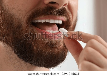 Man with chewing gum on blurred background, closeup Royalty-Free Stock Photo #2291045631