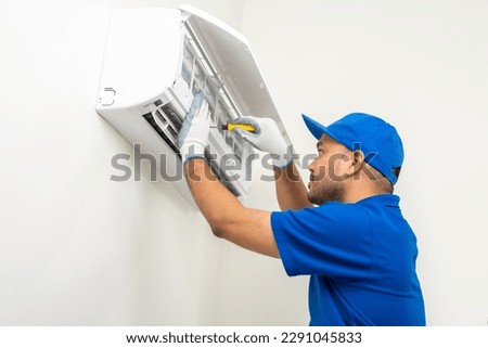 Air conditioner service indoors. Air conditioner cleaning technician He opened the front cover and took out the filters and washed it. He in uniform wearing rubber Royalty-Free Stock Photo #2291045833