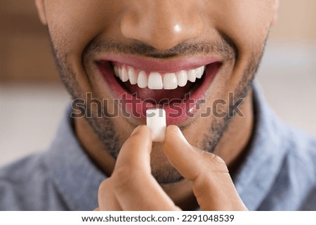 Man with chewing gum on blurred background, closeup Royalty-Free Stock Photo #2291048539