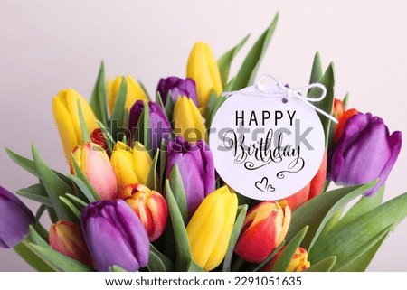 Beautiful bouquet of tulip flowers with Happy Birthday card on light background, closeup Royalty-Free Stock Photo #2291051635
