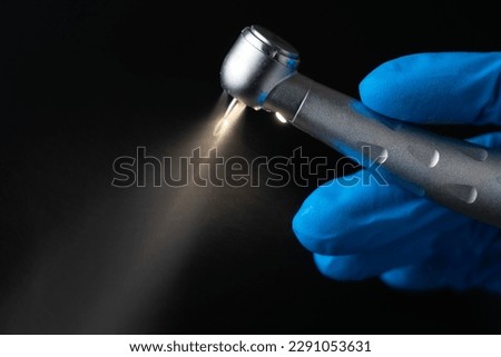 Dentist hand with drill illustrates operation of dentist dental drill machine with water. Dentist's hands with blue gloves working with dental drill in dental office. Close up, selective focus Royalty-Free Stock Photo #2291053631