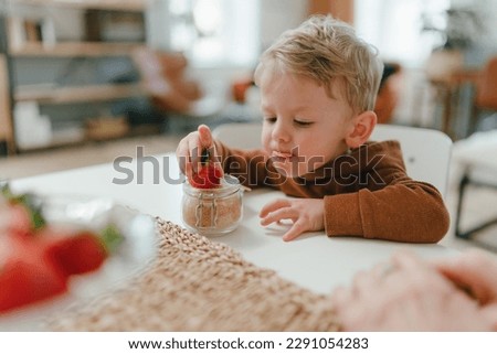 Little boy eating homegrown strawberries with brown sugar. Royalty-Free Stock Photo #2291054283