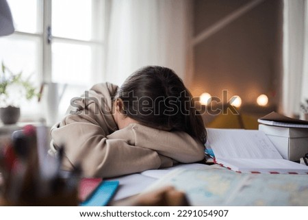 Unhappy girl doing homework in her room. Royalty-Free Stock Photo #2291054907