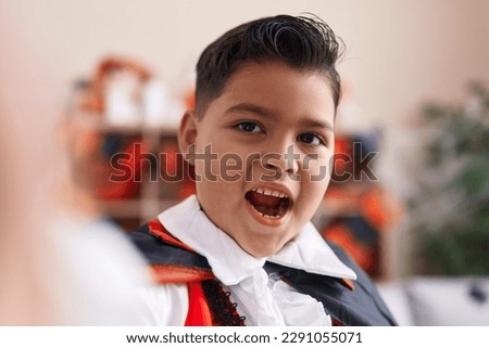Adorable hispanic boy wearing halloween costume make selfie by camera at home