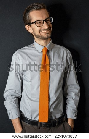 Studio portrait of a businessman with an orange tie and a confident smile.