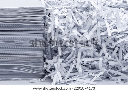 A pile of papers next to scraps from destroyed company documents Royalty-Free Stock Photo #2291074173