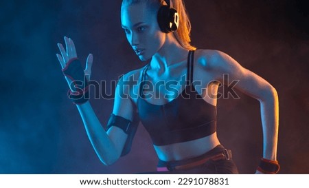 Runner concept. Woman athlete running on black background with neon lights. Fitness and sport motivation. Sprinter run.