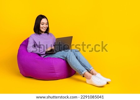 Full length photo of good mood woman wear purple shirt jeans shoes write post letter on laptop isolated on yellow color background