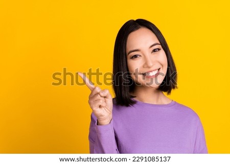 Photo of adorable positive woman wear violet shirt pointing finger empty space isolated yellow color background