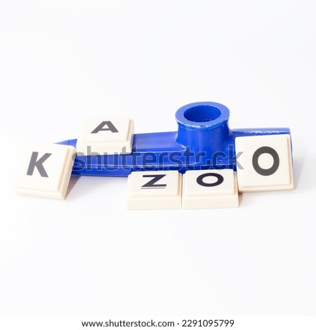 Blue Kazoo. Kazoo lettering isolated on white background. Wind instrument idea concept. Horizontal photo. Educational musical instrument for kids. No people, nobody. Copy space. Blank. 