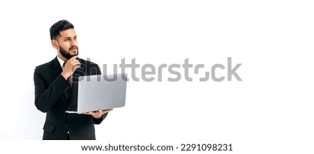 Panoramic photo of puzzled thoughtful elegant arabian or indian man in suit, stand on isolated white background with laptop, pensively looking away, thinking, dreaming.Copy-space for your presentation