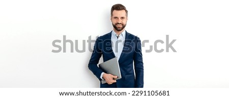 Panoramic portrait of a positive successful caucasian business man in a suit, seo, consultant, broker, stand on isolated white background, holding laptop, looks at camera, smiling friendly. Copy-space