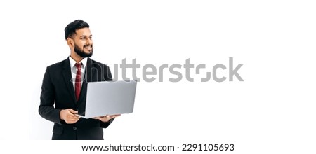 Copy-space. Panoramic photo of positive handsome elegant indian or arabian man in business suit, executive, holding an open laptop in hands, looking aside, stand on isolated white background, smiles