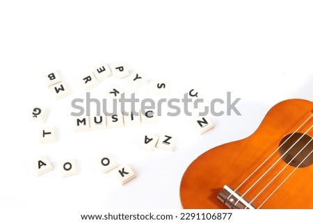 Music idea concept. Music word and ukulele among jumbled letters isolated on white background. Top view photo. Wallpaper. Copy space. Blank area. acoustic four-string instrument. No people, nobody. 