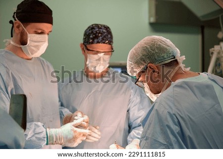 Surgeon face in operating room, stressful operation, surgeon performs operation in modern operating room with activity life support devices and light lamps, life saving, inoperable sarcoma. Royalty-Free Stock Photo #2291111815