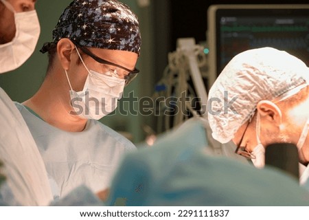 Surgeon face in operating room, stressful operation, surgeon performs operation in modern operating room with activity life support devices and light lamps, life saving, inoperable sarcoma. Royalty-Free Stock Photo #2291111837