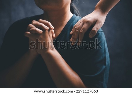 Woman laying hands on a young female christian shoulder to empower and bless him while he feels discouraged in a home office, Christian faith, and christians praying laying on hands concept. Royalty-Free Stock Photo #2291127863