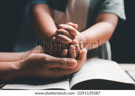 Christian family praying together concept. Child and mother worship God in home. Woman and boy hands praying to god with the bible begging for forgiveness and believe in goodness. Royalty-Free Stock Photo #2291129287