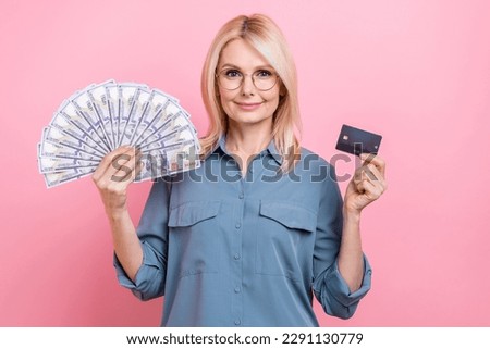 Portrait photo of mature aged pensioner woman wear stylish blue shirt hold bank wireless payment card cashback isolated on pink color background