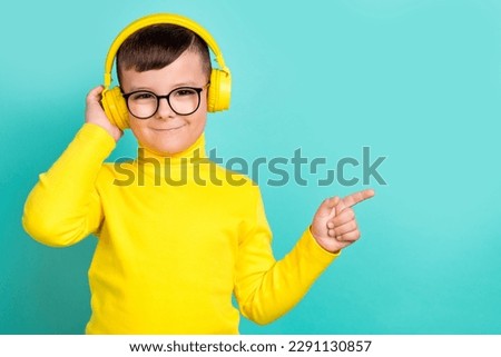 Photo of little boy pointing empty space advertise high quality stereo headset isolated cyan color background