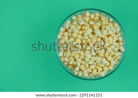 Popcorn large bowl on a green background. Fast food for cinema. Top view. 