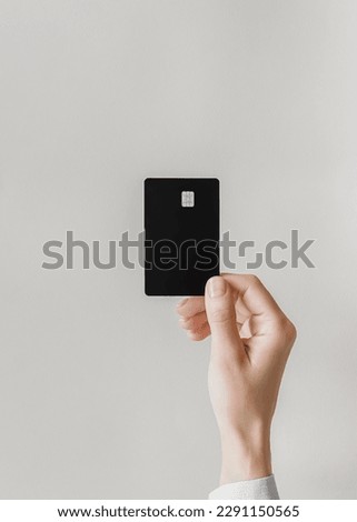 female hand holds a black plastic bank card on a gray background Royalty-Free Stock Photo #2291150565