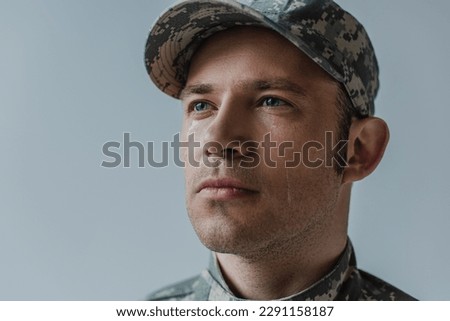 brave soldier in military uniform with teardrop on face isolated on grey