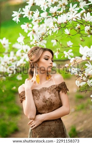 Spring Beautiful romantic girl in fashion  lace dress standing in blooming garden. Dreaming young model between magnolia trees.