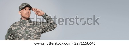 American soldier in military uniform with cap saluting during memorial day holiday isolated on grey, banner Royalty-Free Stock Photo #2291158645