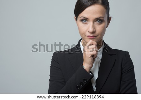 Attractive pensive business woman close-up with hand on chin.