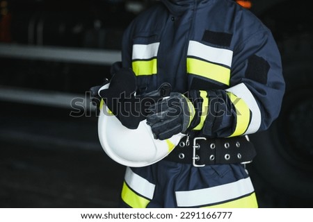 Portrait of a firefighter standing in front of a fire engine.