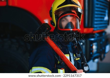 Firefighter portrait on duty. Photo fireman with gas mask and helmet near fire engine