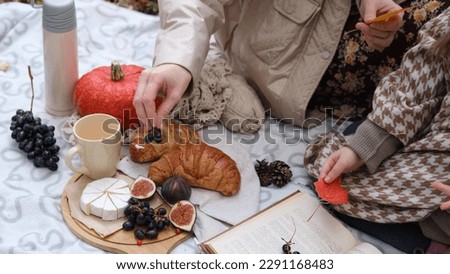 Young mother with her little daughter in an autumn park having picnic