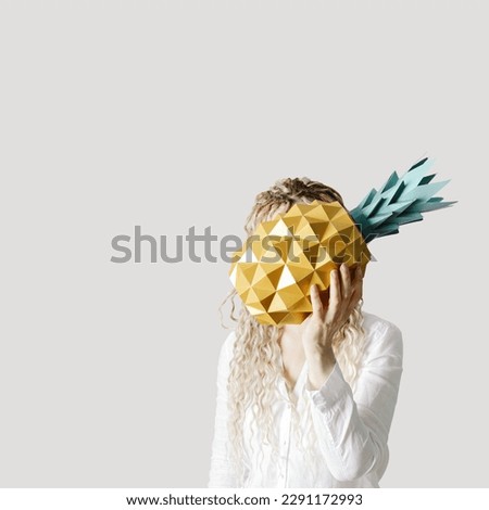 Summer conceptual photo woman hide head in yellow paper pineapple. Girl with long hair hold tropical fruit. Summertime party, celebration, vacation concept, positive mood. Minimal style, trend photo