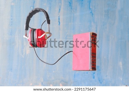 audio book concept with book and vintage headphones floating on blue background, free copy space