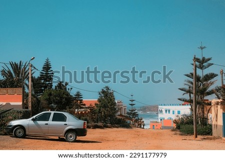 Mirleft, Morocco - relaxed residential neighborhood with low houses, pine trees, and cliffside view of Atlantic Ocean. Dirt path leading to Aftas Beach. Travel day background. Coastal town.