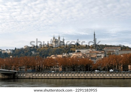 A stunning view of Lyon, France captured from the river, showcasing the iconic Basilica of Notre-Dame de Fourvière perched atop the hill. A beautiful scene that captures the essence of this historic c