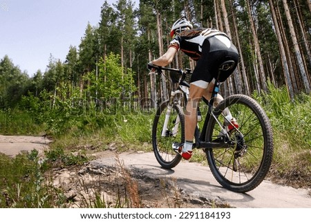 rear view male cyclist riding forest trail on mountainbike, summer cross country cycling race