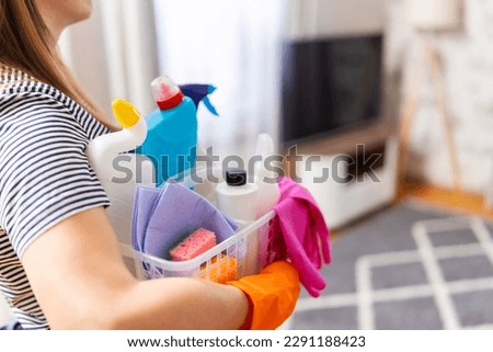 Woman in rubber gloves with basket of cleaning supplies ready to clean up Royalty-Free Stock Photo #2291188423